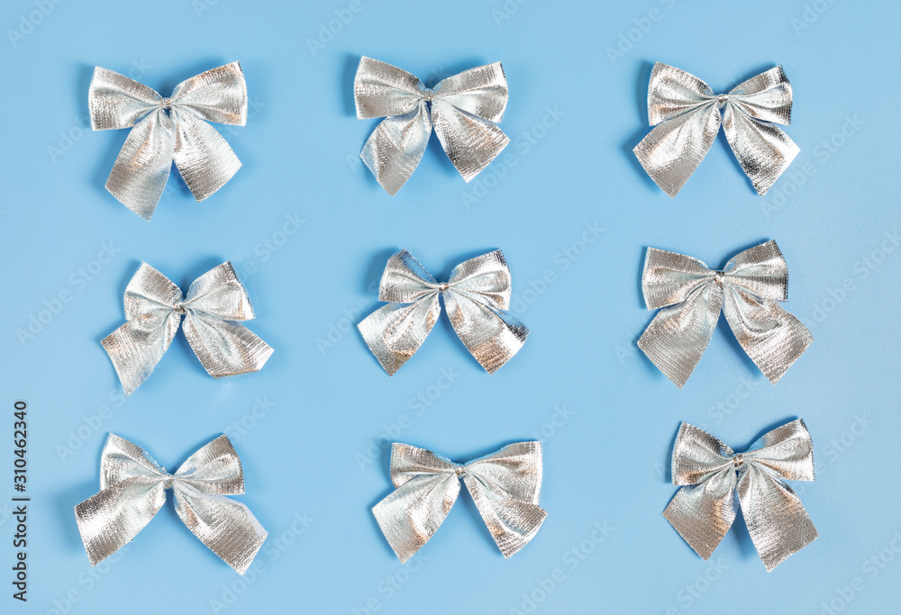 Christmas pattern with silver bows on pastel blue background.