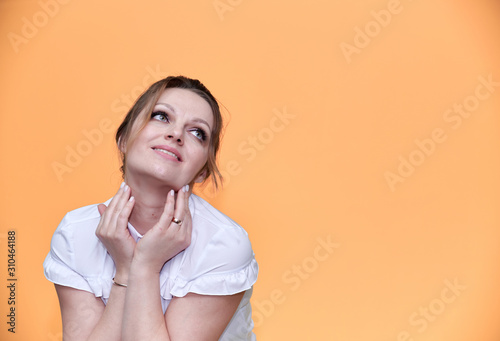 Business concept. Close-up portrait of an adult pretty woman of 40 years old with good makeup in a business suit on a yellow background. Standing right in front of the camera with a smile.