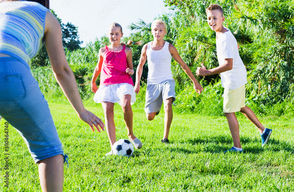 Obraz premium Three happy kids playing with ball outdoors, running together