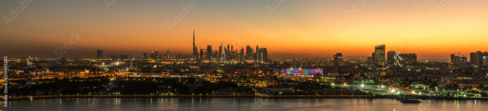 Fototapeta premium Dubai susnet over the creek in the background the silhouette of the tall buildings 