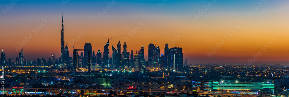 Dubai susnet over the creek in the background the silhouette of the tall buildings 