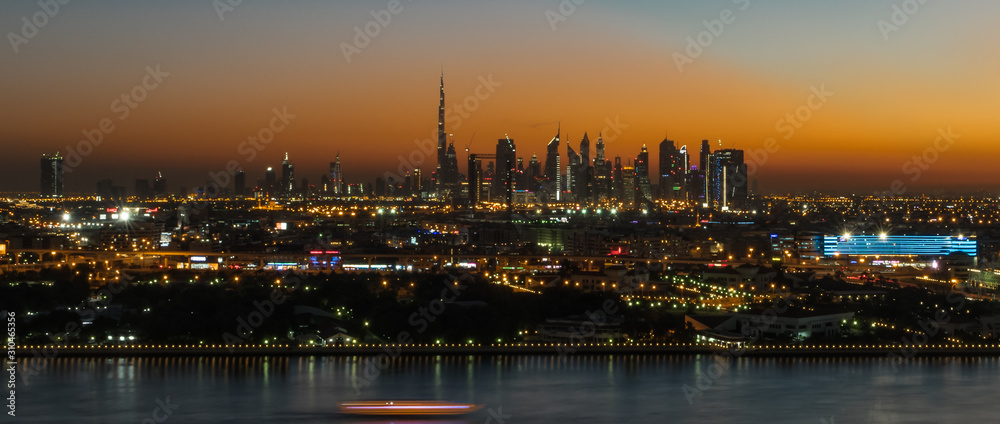 Dubai susnet over the creek in the background the silhouette of the tall buildings 