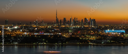 Dubai susnet over the creek in the background the silhouette of the tall buildings  © Joerg