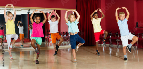 Childrens trying balance movements of ballet in classroom