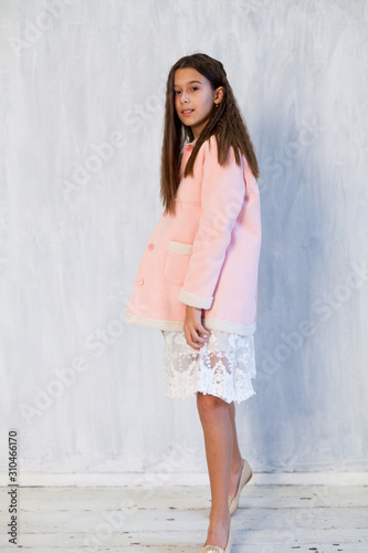 Portrait of a beautiful fashionable girl in a pink jacket and white dress