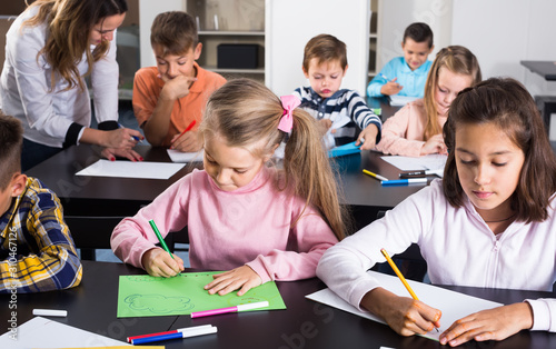 calm little children with teacher drawing in classroom