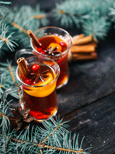 Two glasses with traditional winter or new year hot mulled wine drink with tangerines cinnamon anise on the table