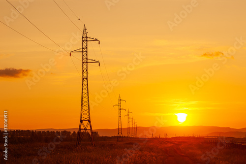 High voltage electric poles in the field against sunset sky