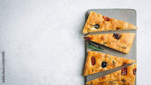 Traditional Italian Focaccia with tomatoes, olives and rosemary - homemade flat bread focaccia.