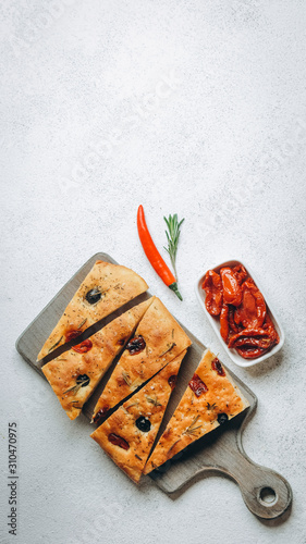 Traditional Italian Focaccia with tomatoes, olives and rosemary - homemade flat bread focaccia.
