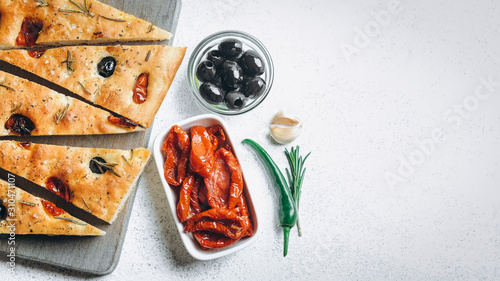 Traditional Italian Focaccia with tomatoes, olives and rosemary - homemade flat bread focaccia.