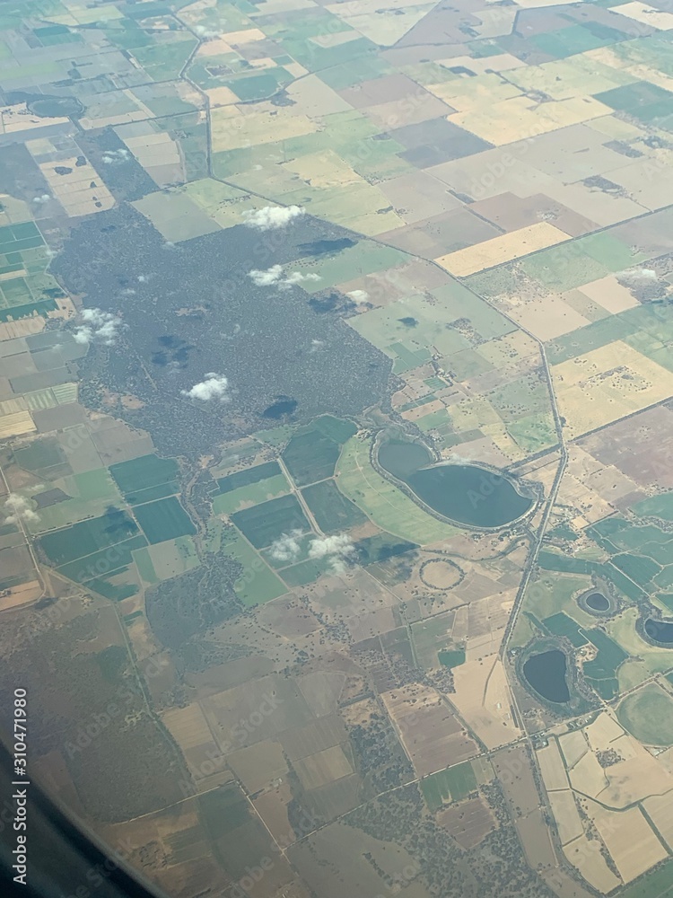 Fototapeta premium Dark fields in the rough shape of a person as seen from a plane