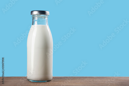 Bottle of milk on a wooden table on a blue background.