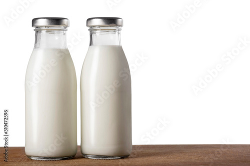 Two bottles of milk on a wooden table isolated on white.