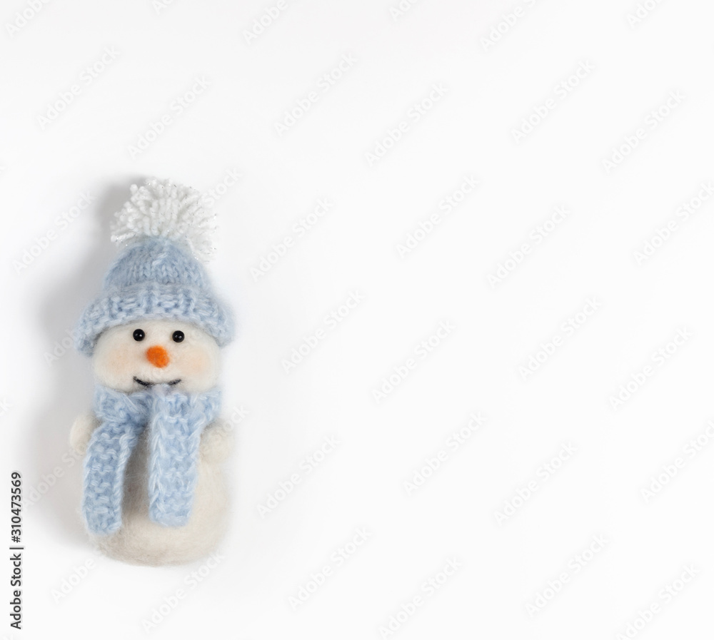 Cute funny snowman in blue hat and scarf on white background. Christmas wool toy. Cute funny snowman in blue hat and scarf on white background. Christmas wool toy.