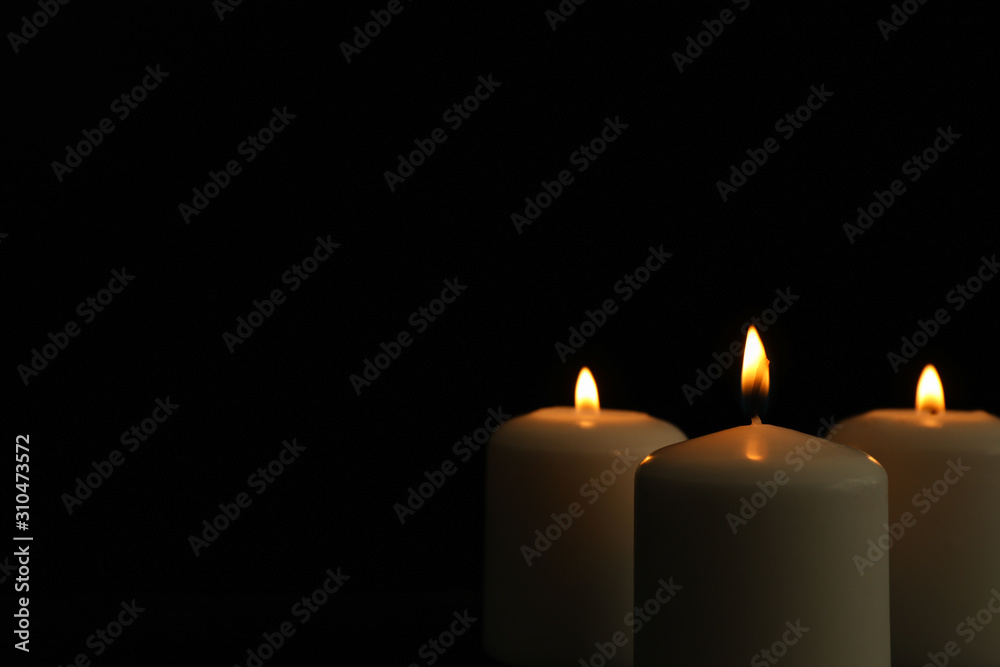 Glowing candles on black background, space for text Glowing candles on black background, space for text