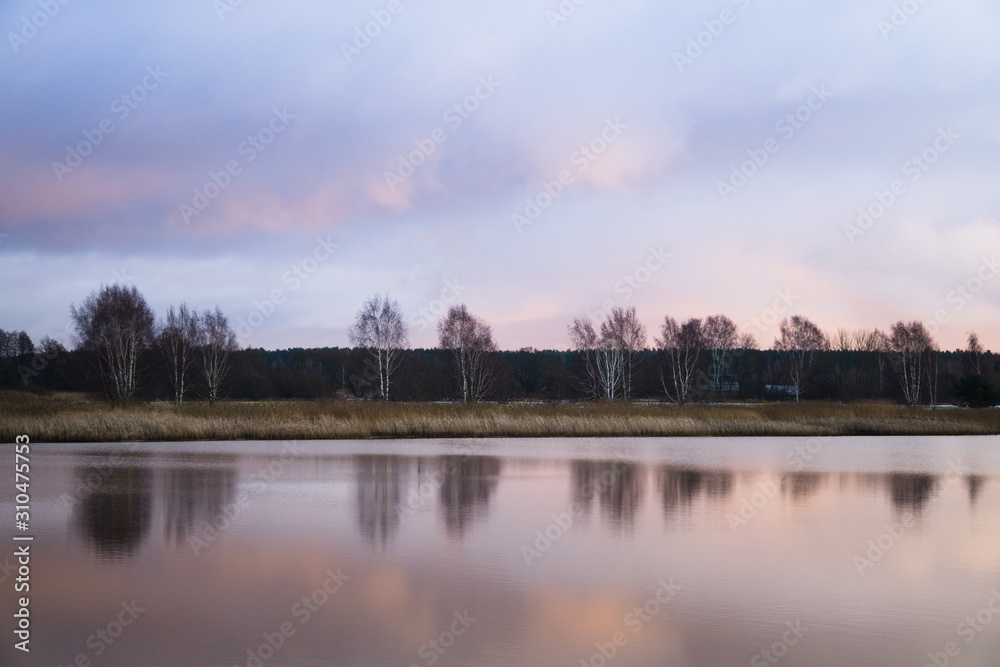 Reflection of trees in a calm surface of the river, in the early morning.