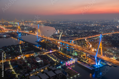 Evening bridge with lights on the bridge over the Chao Phraya River. Aerial view of the Bhumibol Adulyadej Suspension Bridge over the Chao Phraya River in Bangkok with cars on the bridge at the sunset © Sathit Trakunpunlert