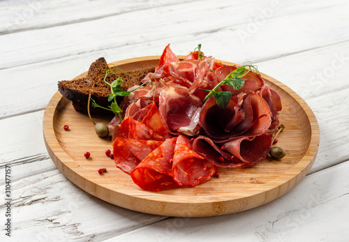 sliced bacon, meat and salami on a white wooden background