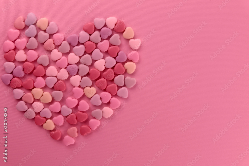 Valentine's day background. Big heart laid out of small hearts on a pink background. Toning pink. Top view, horizontal, close-up, free space on the right. Valentine's day background. Big heart laid out of small hearts on a pink background. Toning pink. Top view, horizontal, close-up, free space on the right.