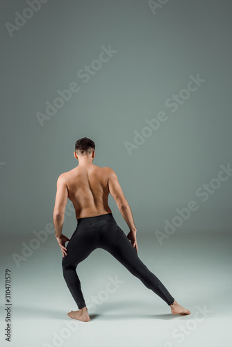 back view of dancer in black leggings dancing contemporary on dark background © LIGHTFIELD STUDIOS