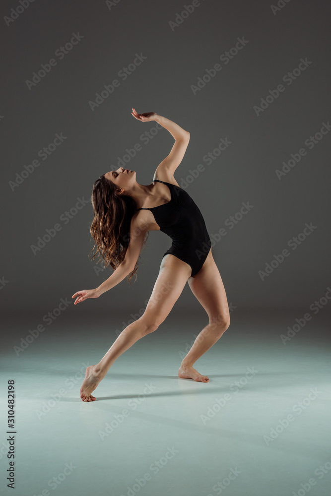 attractive dancer in black bodysuit dancing contemporary on dark background