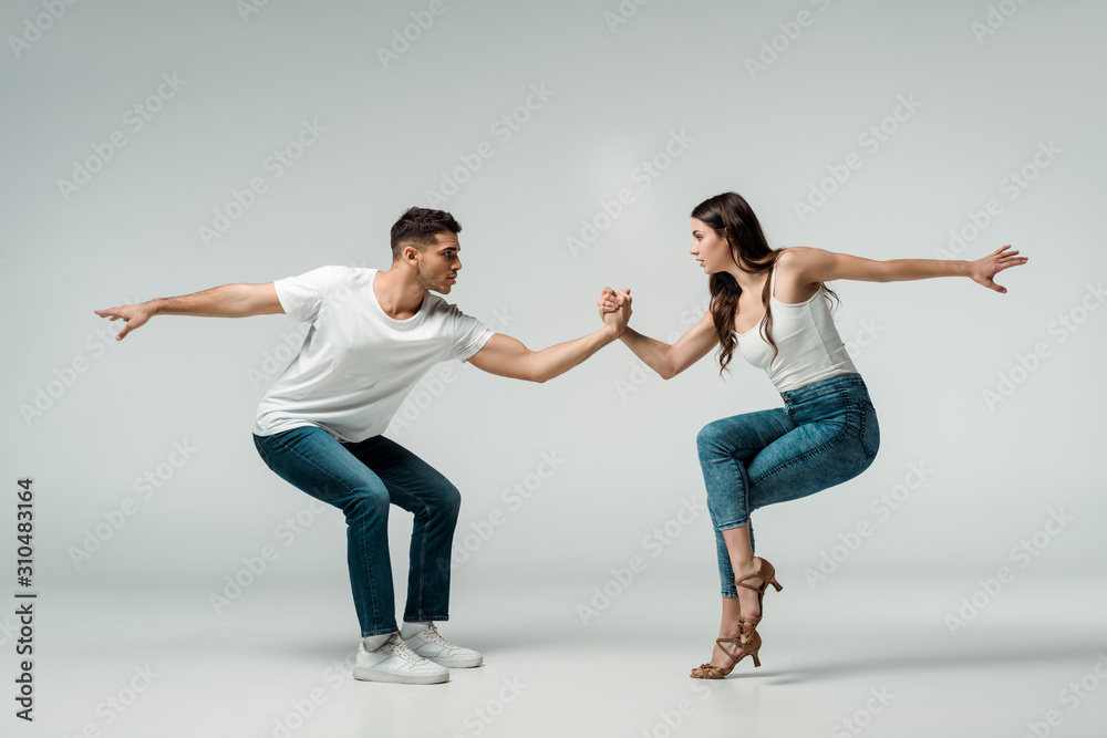 side view of dancers in denim jeans dancing bachata on grey background side view of dancers in denim jeans dancing bachata on grey background