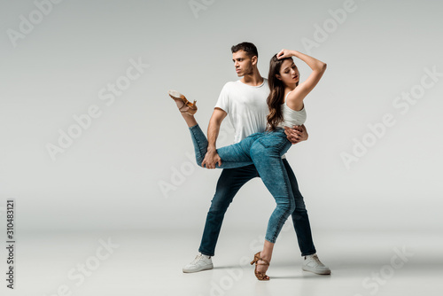 dancers in denim jeans dancing bachata on grey background