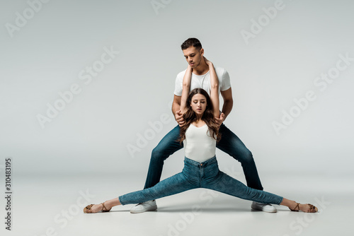 dancers in denim jeans dancing bachata on grey background