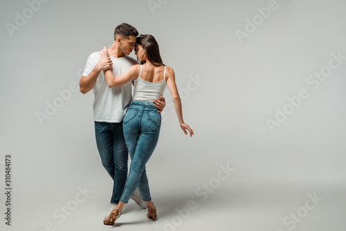 dancers in denim jeans dancing bachata on grey background photo