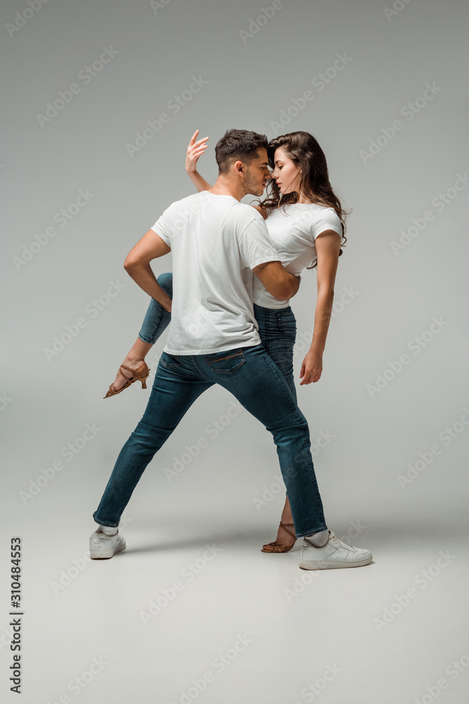 dancers in t-shirts and jeans dancing bachata on grey background dancers in t-shirts and jeans dancing bachata on grey background