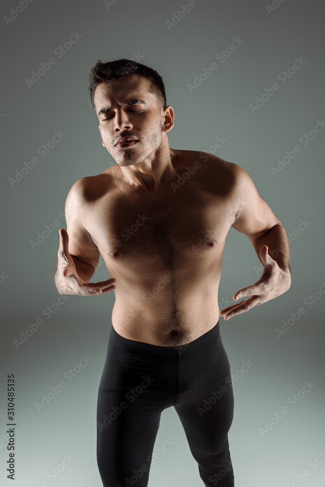 handsome dancer with closed eyes in black leggings dancing contemporary on grey background