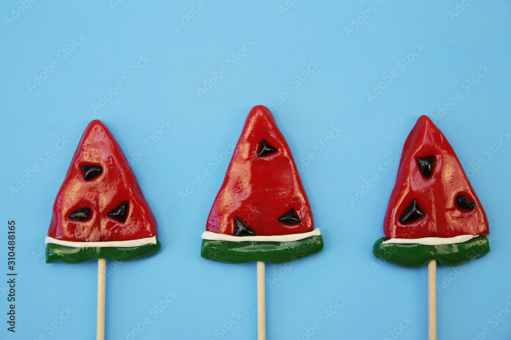 lollipops in the form of a slice watermelon isolated on a blue background. Confectionery background. The concept of holidays and gifts. Top view. Flat lay. With copy space for text.