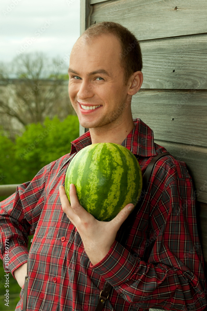 Fototapeta premium Young farmer holding a fresh watermelon