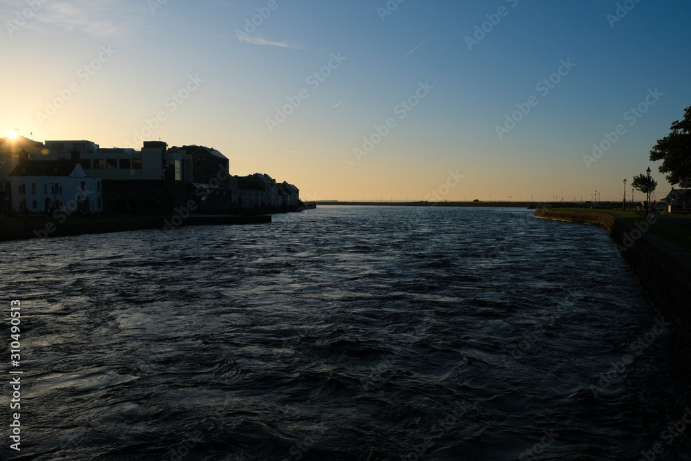 Galway city at sunrise - taken from the Claddagh, showing the harbor and buildings on a clear morning by the River Corrib