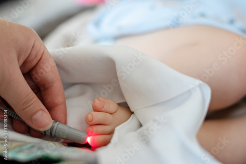 Doctor performs laser therapy on the baby patients toe in rehabilitation centre. Low level laser therapy. Biostimulation. Treatment of musculoskeletal disorders. photo