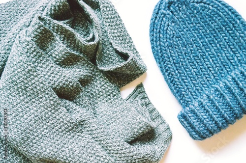 Gray woolen scarf and blue knitted hat. Flat lay fashion photography. Closeup winter clothes. Trendy knitwear