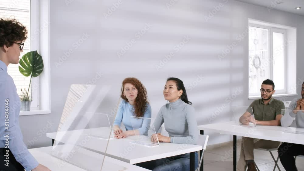 Medium arc shot of multinational students sitting in classroom with transparent AR tablets, Asian woman asking question and laughing, and female teacher with curly hair answering. Suitable for AR, VR. Medium arc shot of multinational students sitting in classroom with transparent AR tablets, Asian woman asking question and laughing, and female teacher with curly hair answering. Suitable for AR, VR.