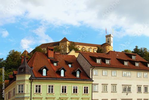 Scenic landscape of Ljubljana at sunny autumn day. Medieval colorful buildings along the promenade of the Ljubljanica River. Ancient Ljubljana castle at the top of the hill. Ljubljana, Slovenia