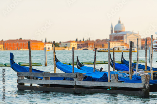 Gold sunset with gondolas docked in Grand Canal, Venice, Italy. Bright sunny panorama view of Grand Canal with gondola and church. Beautiful photo background of the venetian canal in the morning. © YOUproduction