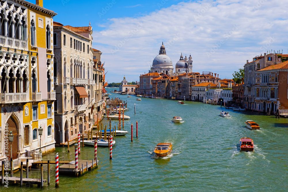 Beautiful view of famous Grand Canal with Basilica di Santa Maria della Salute and traditional gondolas summer day in Venice, Italy. Panoramic view of Canal Grande. Romantic city on water.