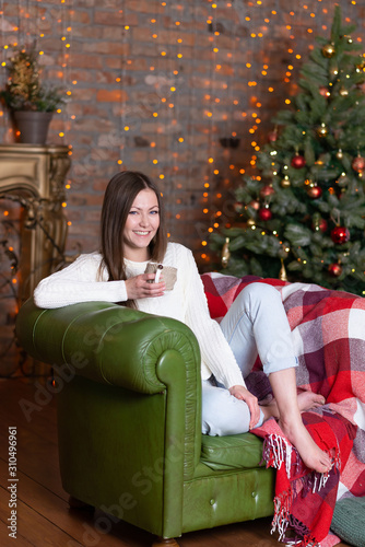portrait of a fashionable young blue-eyed brunette in a light knitted sweater and blue jeans. 2020
