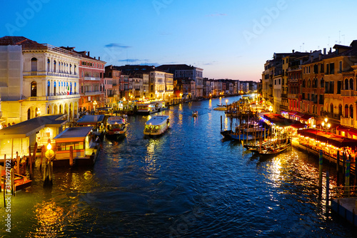 Grand Canal in Venice, Italy at night. View on gondolas and city lights from Rialto Bridge. Beautiful and romantic Italian city on water.