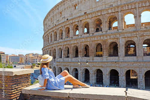 Canvastavla Travel woman in romantic dress and hat sitting and looking on Coliseum, Rome, Italy