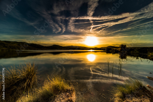 sunset in the lake, reflection of the sun and plants in the water