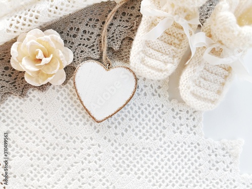 Baby booties and heart-shaped decoration on a knitted base. Place for text. Greeting card. 