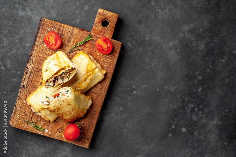 Mexican burrito wraps with chicken and vegetables on a cutting board, on a background of concrete, mexican shawarma