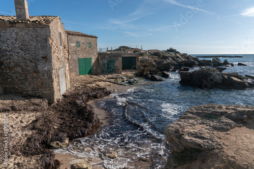 Old fishermen's stone traditional huts in the Majorcan cove of Can Curt, with sand and rocks, near Colonia de Sant Jordi, Ses Salines.