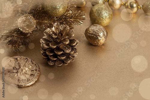 Christmas or New Year composition. Christmas tree branches with a toy, pine cone, cookies and orange slice in gold color with bokeh. Holiday and celebration concept for greeting card or invitation
