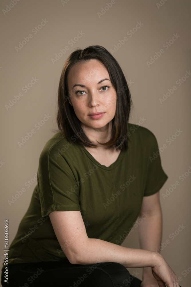 casual portrait of young woman on taupe backdrop casual portrait of young woman on taupe backdrop